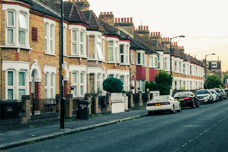 A white commercial van with the logo 'DHL' on the front is parked on a city street in Hounslow, surrounded by historic multi-storey buildings with brick and stone facades, large windows, and decorativ